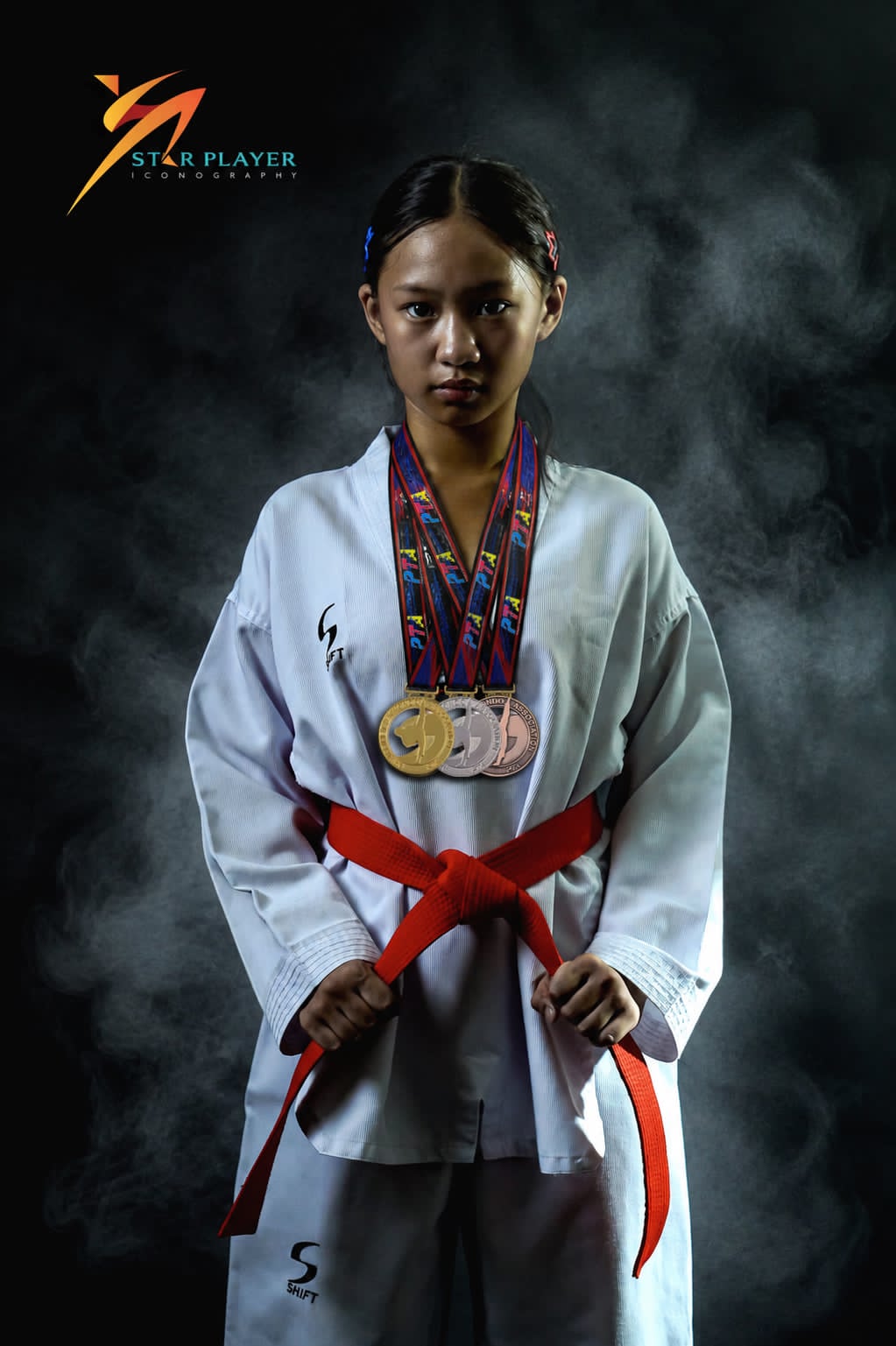Taekwondo athlete posing with medals in the studio